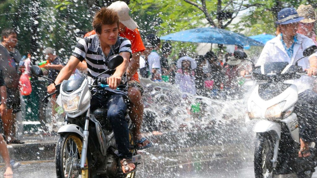 Rollerfahrer in Thailand, die an Songkran mit Wasser beworfen werden