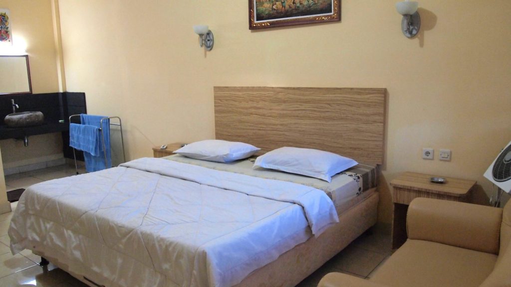 Einfaches Hotelzimmer in Indonesien mit Klimaanlage und Ventilator, Fernseher, Warmwasser und Schreibtisch