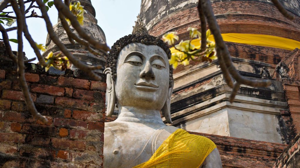Ein großer Buddha vor einem Chedi in Ayutthaya