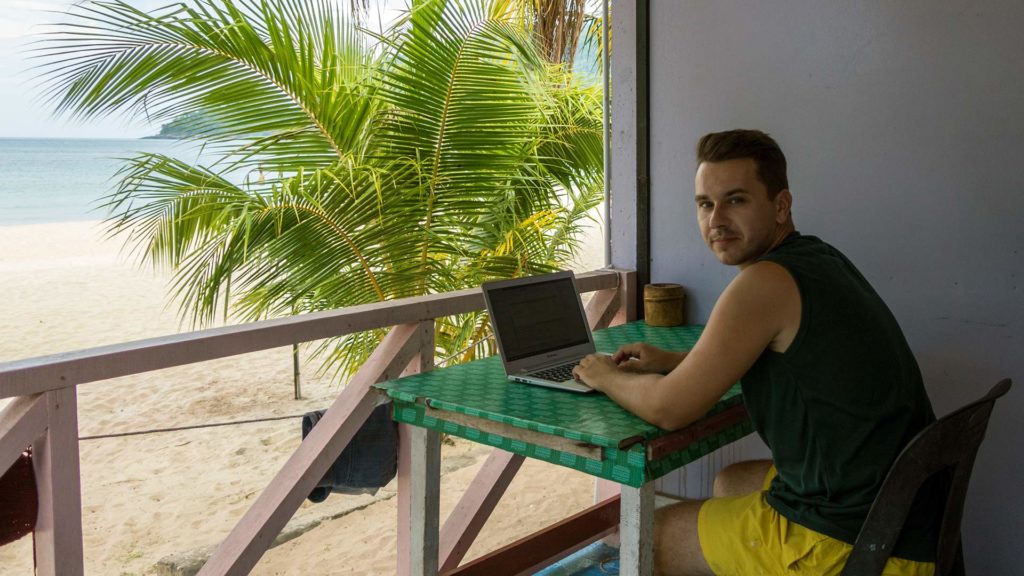 Marcel mit seinem Laptop beim Arbeiten am Strand am Juara Beach