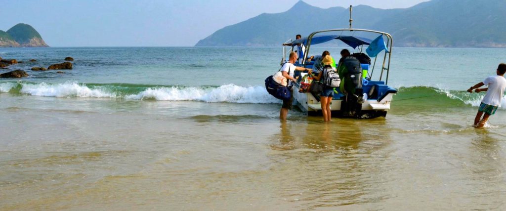 Boat with tourists arrives at Sai Wan Beach in Hong Kong