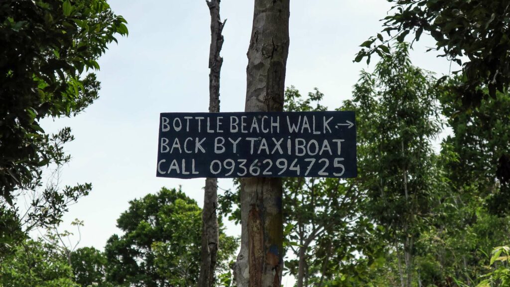 Schild im Dschungel mit Telefonnummer für ein Taxi Boat am Bottle Beach