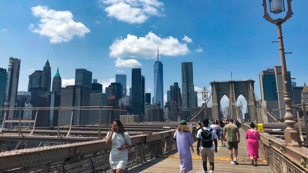 Walking over the Brooklyn Bridge in New York City with the skyline in the background