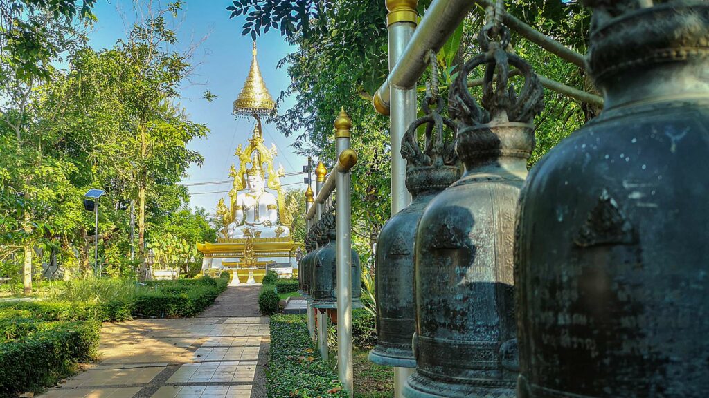 Weißer Buddha und Glocken im Tempel Wat Phrathat Kham Kaen