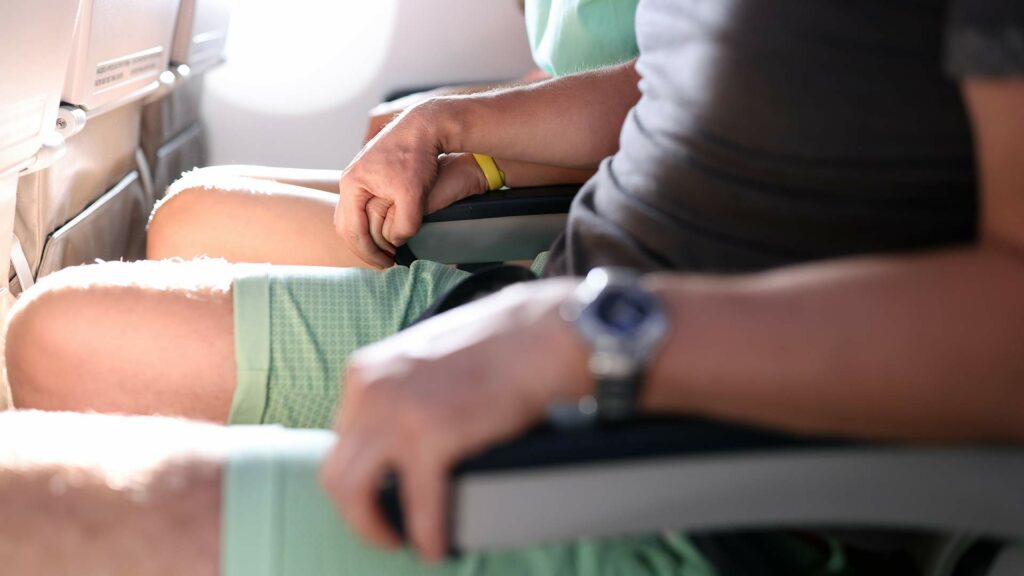 Passagiere mit Flugangst halten sich am Flugzeugsitz fest